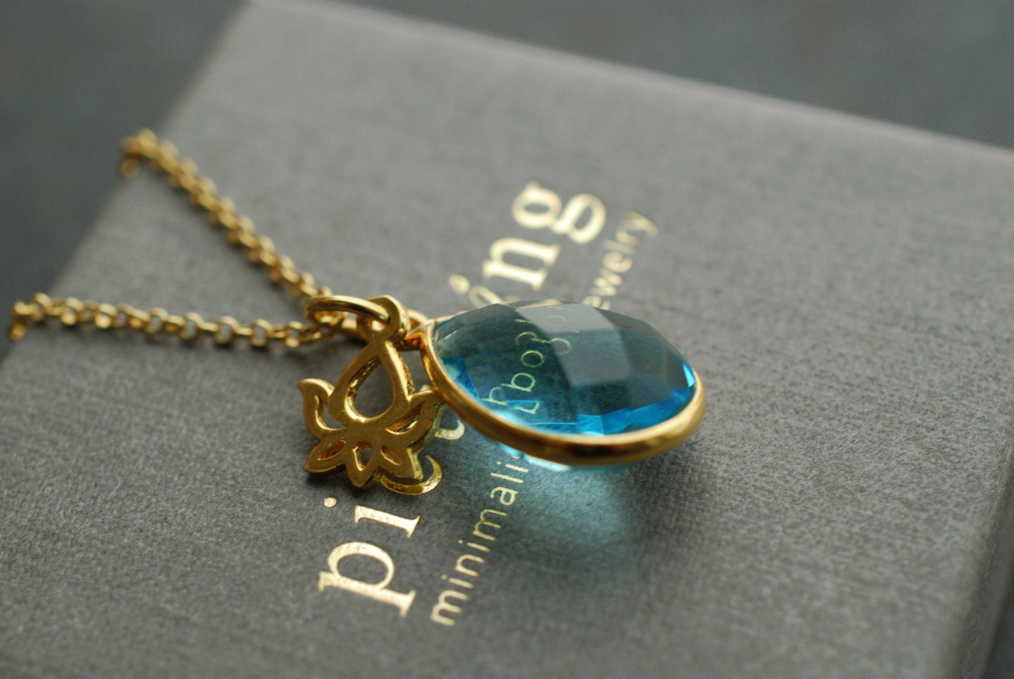 NAMASTE . Vergoldete Kette mit Edelstein-Tropfen Blauer Topas und Lotus-Anhänger